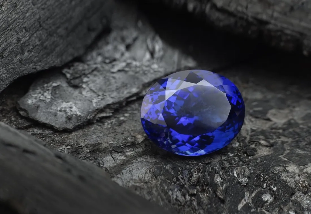 A blue sapphire resting on a black rock, showcasing the beauty of Tanzanite gemstone