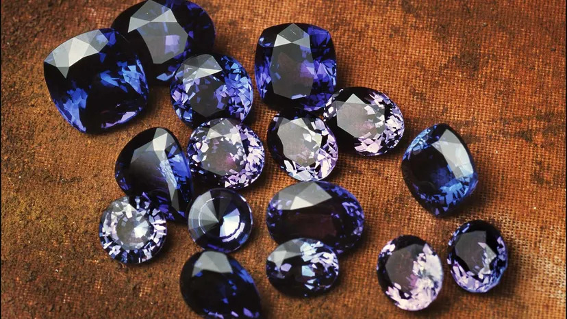 A cluster of purple sapphire stones resting on a brown surface. The image showcases the beauty of these gemstones